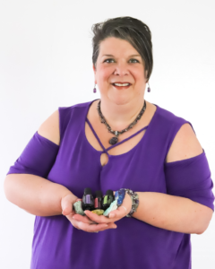 An Image of Yvette LeFlore from Healing with Yvette holding crystals with a purple top and white background.